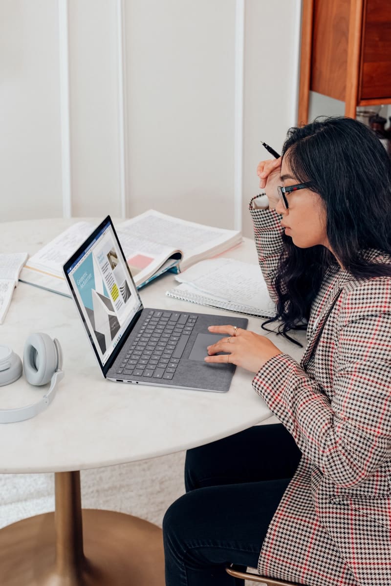 woman in red and white plaid dress shirt using microsoft surface laptop